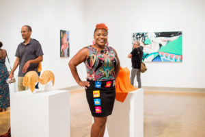 woman posing in art gallery, stickers of various colors adorn her skirt
