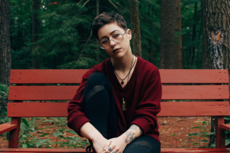 Image of woman wearing glasses sitting down on a bench