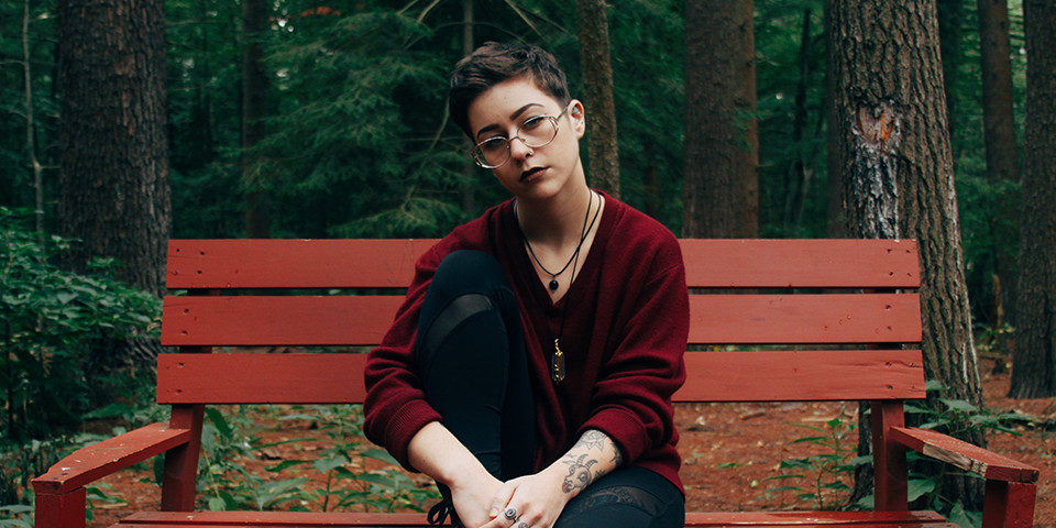 Image of person wearing glasses sitting down on a bench