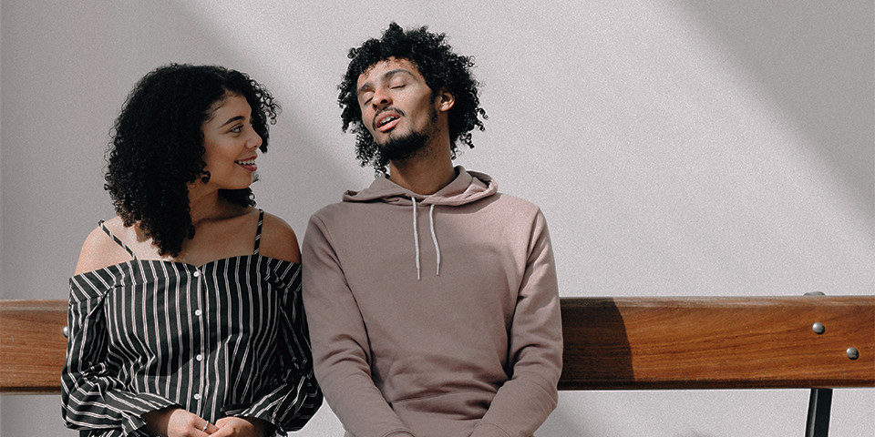 black man and woman sit on bench chatting