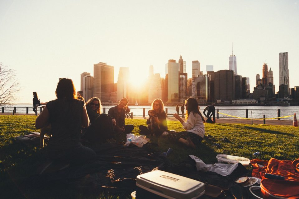 friends sit together on picnic blanket in front of city skyline
