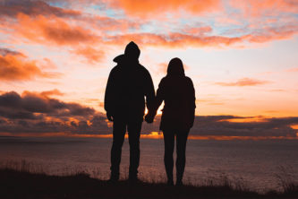 Couple holding hands at they watch the sunset