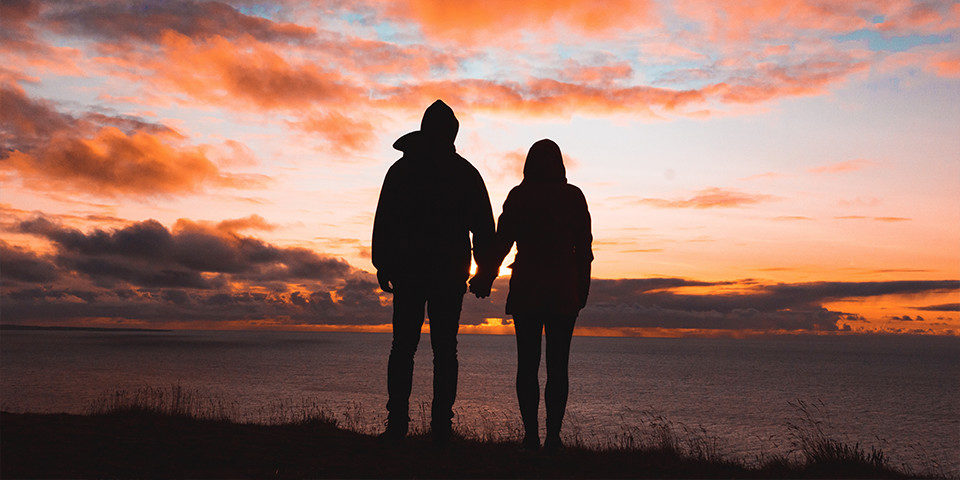 Couple holding hands at they watch the sunset